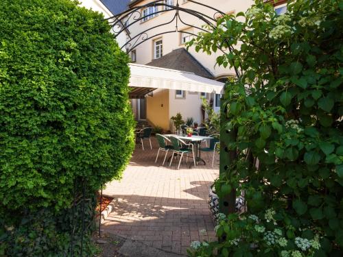 un jardín con mesa y sillas detrás de un seto en Hôtel - Restaurant " Victor Hugo", en Vianden