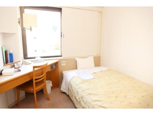 a bedroom with a desk and a bed and a desk and window at Mizusawa Ground Hotel - Vacation STAY 84945 in Oshu