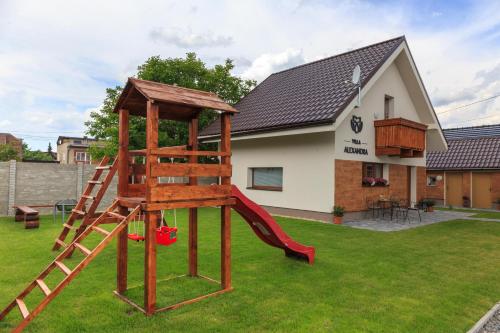 een speeltuin met een glijbaan in een tuin met een huis bij Villa Michaela in Bešeňová