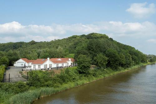 uma casa numa colina ao lado de um rio em Bed & Breakfast Trouwborst em Rhenen