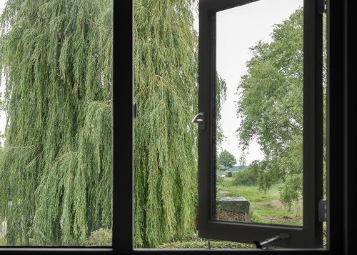 een raam met uitzicht op een treurwilg bij Gieters Geluk in Giethoorn