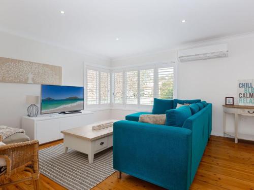 a living room with a blue couch and a tv at Rubys Retreat, 44 Achilles Street - pet friendly, aircon, wifi & boat parking in Shoal Bay