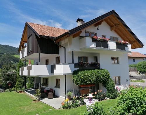 ein großes weißes Haus mit Balkonen und Blumen in der Unterkunft Appartements Oberleiter in Olang