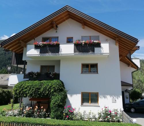 ein weißes Haus mit Blumen auf den Balkonen in der Unterkunft Appartements Oberleiter in Olang