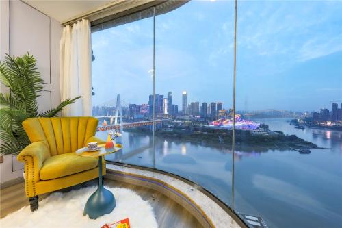 een gele stoel in een kamer met een groot raam bij Baihong.Riverview Apartment in Chongqing