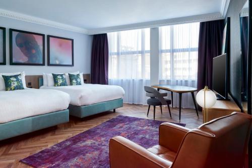 um quarto de hotel com duas camas e uma mesa em NYX Hotel London Holborn by Leonardo Hotels em Londres