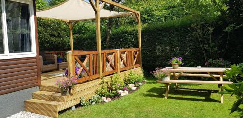 a wooden deck with a table and a gazebo at vakantiehuis op de veluwe in Wolfheze