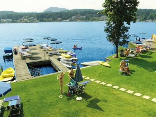 フェルデン・アム・ヴェルターゼーにあるBarry Memle Directly at the Lakeの湖の桟橋の近くの芝生に座る人々