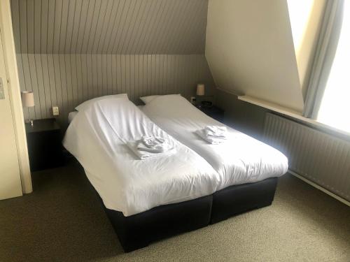 een bed met witte lakens in een kamer met een raam bij Hotel Grandcafe De Doelen in Franeker