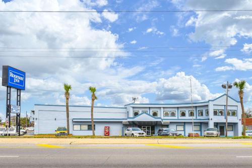 ein weißes Gebäude mit Palmen vor einer Straße in der Unterkunft Rodeway Inn in Metairie