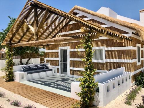 ein Haus mit einer Holzterrasse mit einer Pergola in der Unterkunft Cabana 2 da Comporta in Comporta