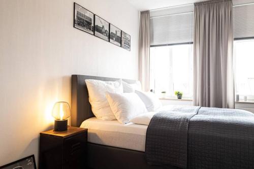 een slaapkamer met een bed met witte kussens en een lamp bij Luxus-Apartment in Leipzig mit Privat-Parkplatz in Leipzig