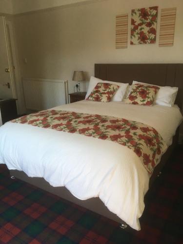 een groot bed met witte lakens en rode kussens bij Moraydale Guest House in Elgin