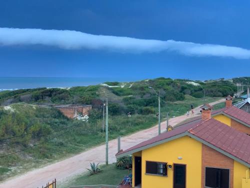 ein gelbes Haus an der Seite einer unbefestigten Straße in der Unterkunft Complejo Casas del Mirador in Barra del Chuy