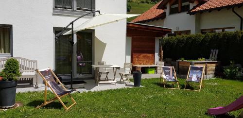 een groep ligstoelen en een parasol in een tuin bij Ferienhaus Gundi in Pettneu am Arlberg