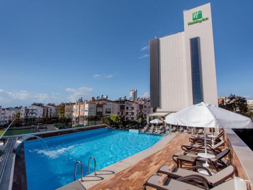 una piscina en la azotea de un edificio con tumbonas en Holiday Inn Antalya - Lara, an IHG Hotel, en Antalya