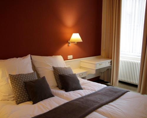 een slaapkamer met een bed met witte lakens en kussens bij Z&B Hotel in Trier