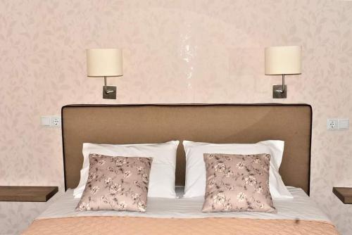 a bed with two pillows and two lamps above it at Studios Thea Fresh Rooms Thassos in Limenas