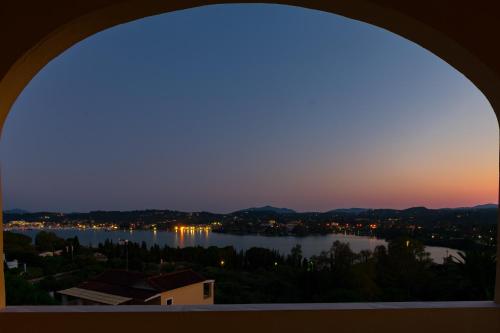 een raam met uitzicht op een meer bij zonsondergang bij Elite Corfu Sea View Rooms in Corfu-stad