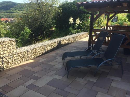 un patio con 2 sedie e un muro in pietra di Ferienwohnung Saaletalblick a Jena