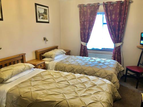 una camera d'albergo con due letti e una finestra di Atlantic Guest House a Donegal