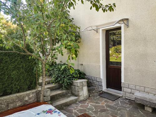 ein Haus mit einem Baum und Treppen neben einer Tür in der Unterkunft Apartment & rooms Grmek in Postojna