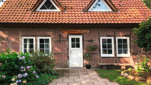 een stenen huis met een oranje dak en een witte deur bij Ferienhof Cohrs in Bispingen