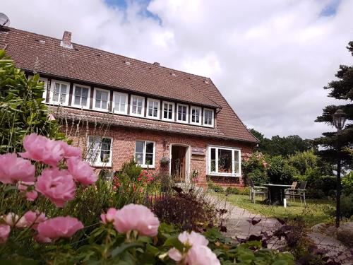 een bakstenen huis met roze rozen ervoor bij Ferienhof Cohrs in Bispingen