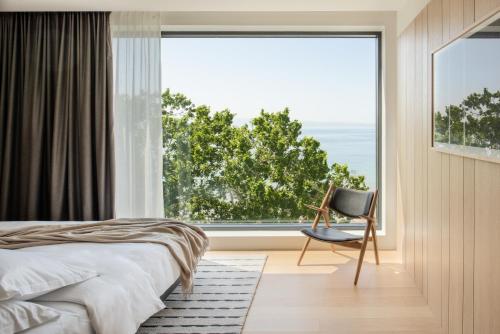 a bedroom with a bed and a chair and a large window at briig boutique hotel in Split