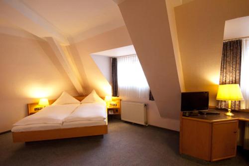 um quarto de hotel com uma cama e uma televisão em Hotel Goldinger em Landstuhl