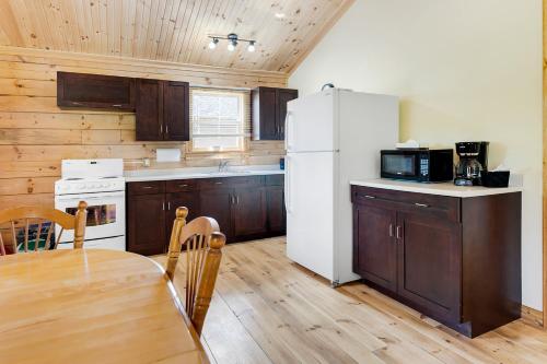 een keuken met een tafel en een witte koelkast bij Ingonish Chalets in Ingonish Beach