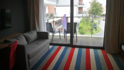 ein Wohnzimmer mit Sofa und Blick auf einen Balkon in der Unterkunft Hotel Skipper in Rewa