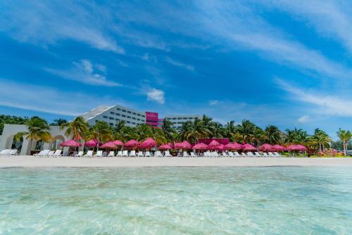 una spiaggia con ombrelloni rosa e un resort di Grand Oasis Palm - All inclusive a Cancún