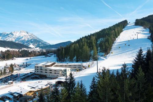 une piste de ski couverte de neige avec une station de ski dans l'établissement TUI BLUE Fieberbrunn, à Fieberbrunn