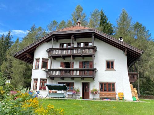 uma grande casa branca com varanda e árvores em Im weißen Schlössl Friedemann em Rasùn di Sotto