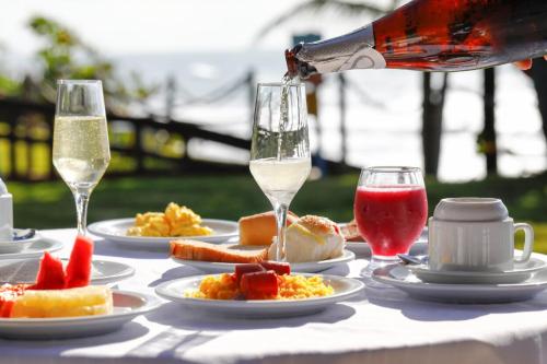 una tavola con piatti di cibo e bicchieri di vino di Pousada Ecoporto a Porto De Galinhas