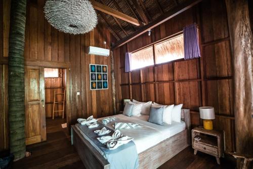 a bedroom with a bed in a wooden wall at Gili Treehouse in Gili Trawangan