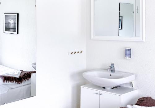 a white bathroom with a sink and a mirror at Löderup Strandbad Hotell och Restaurang in Löderup