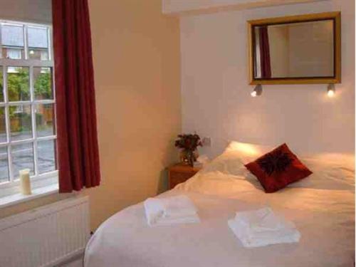 1 dormitorio con 1 cama blanca y ventana en The Wheatsheaf Inn, en Cuckfield