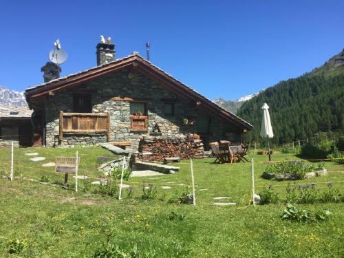 una baita di tronchi in un prato con una casa di CHALET GORRET CHENEIL a Valtournenche