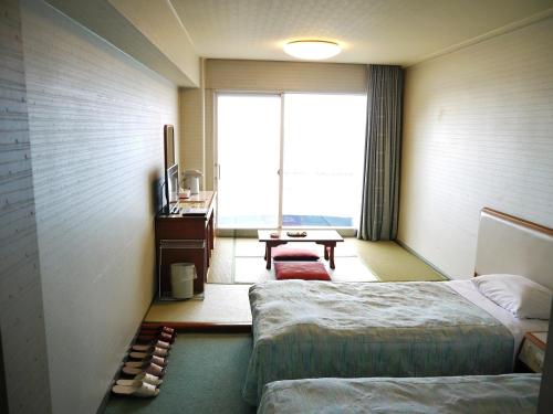 Cette chambre comprend 2 lits et une fenêtre. dans l'établissement Nishiizu Matsuzaki Itoen Hotel, à Matsuzaki