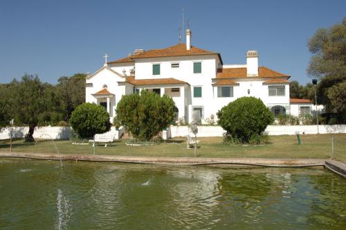 una gran casa blanca junto a un cuerpo de agua en Elxadai Parque, en Elvas