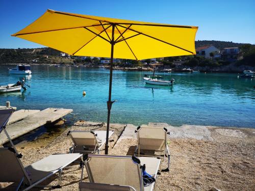 un gruppo di sedie e un ombrellone su una spiaggia di Villa Ivan a Rogoznica (Rogosnizza)