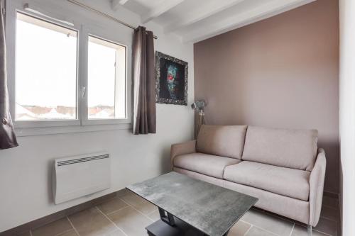 ein Wohnzimmer mit einem Sofa und einem Tisch in der Unterkunft Roissy Appartements in Roissy-en-France