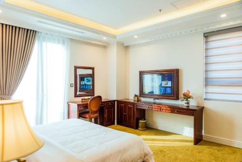 um quarto com uma cama, uma secretária e uma televisão em THE SHINE HOTEL em Haiphong