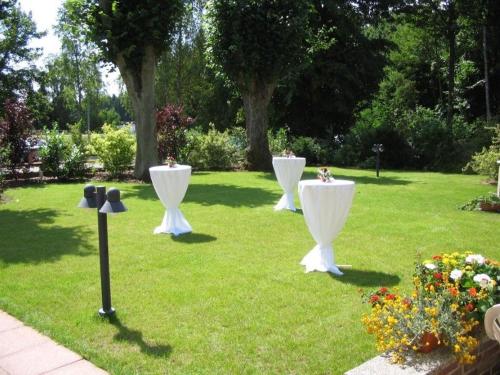 three white tables in the grass in a garden at Waldhotel Riesebusch in Bad Schwartau