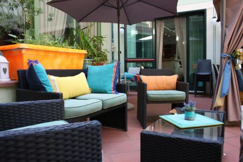 een patio met stoelen en tafels en een parasol bij Hotel Ambrosiano in Montecatini Terme