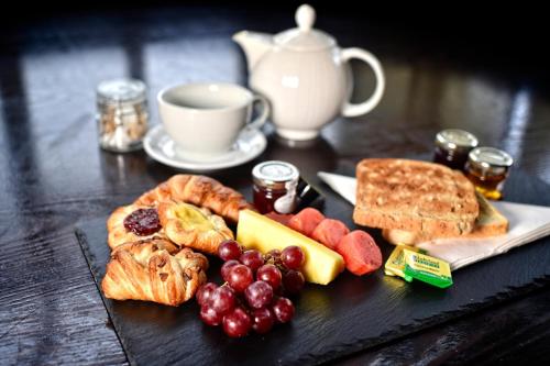 une assiette de nourriture avec du raisin, du pain et une tasse de café dans l'établissement Red Hall Hotel, à Walmersley