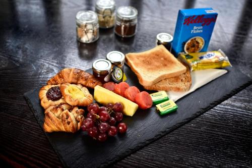 - une assiette noire de nourriture avec du pain de raisin et du pain grillé dans l'établissement Red Hall Hotel, à Walmersley