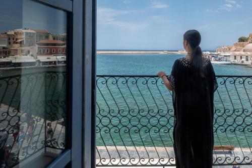 Una donna che guarda fuori da una finestra verso l'acqua di Elia Zampeliou Hotel a Chania